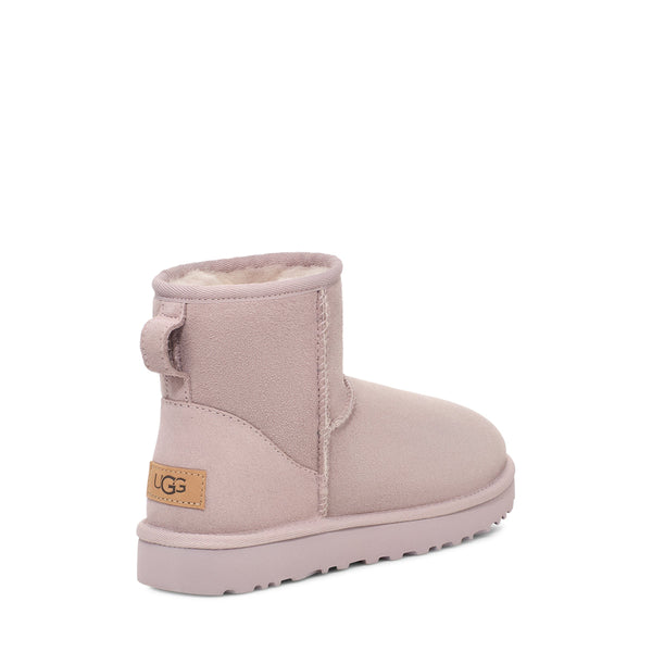 A pink short boot with a rounded toe and a plush lining on a white background.