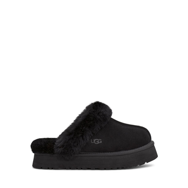 Black UGG slipper with fluffy lining on a white background.