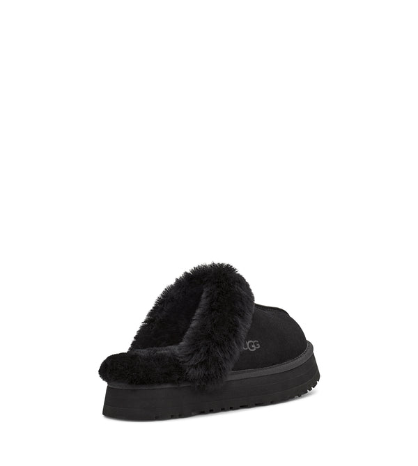 Black fluffy slipper with brand logo on a white background.