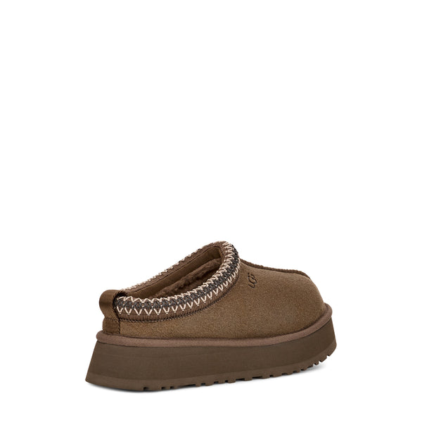 Brown slip-on shoe with decorative stitching and thick sole, isolated on white background.