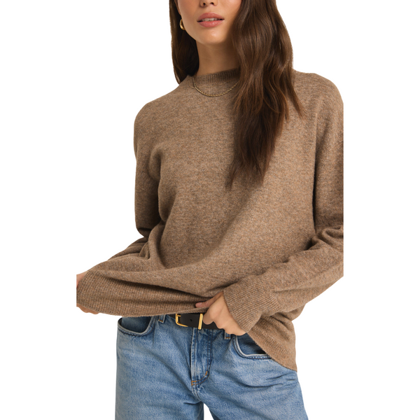 Woman in a brown turtleneck sweater and blue jeans.