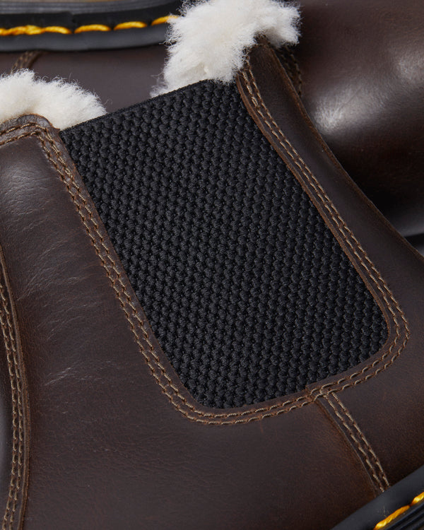 Close-up of a brown winter boot with black elastic side panels and fluffy white lining.