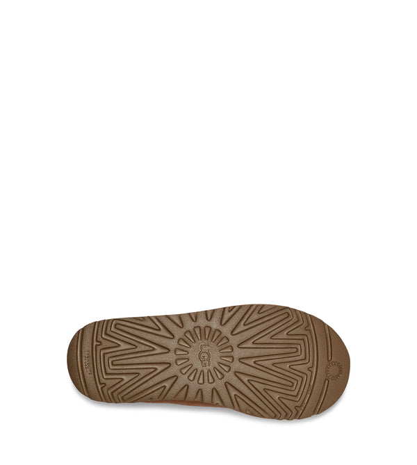 Bottom view of a single tan slip-on shoe with decorative stitching on a white background.