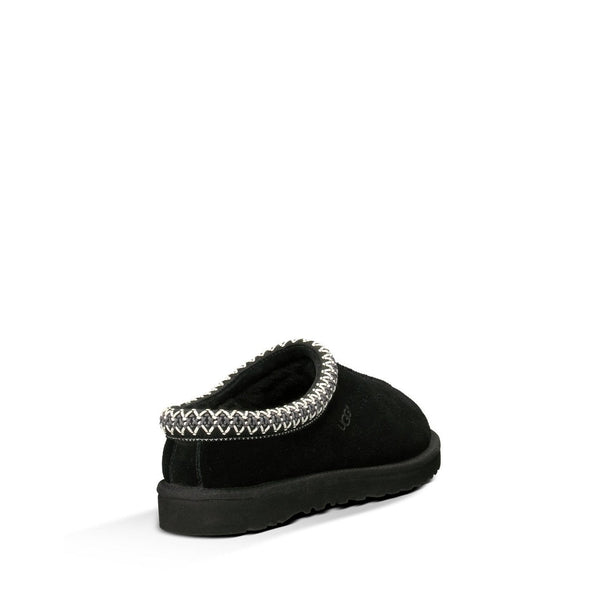 Black UGG slipper with braided trim detail on a white background.