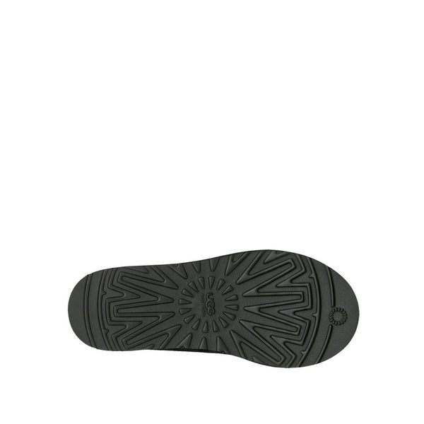 Black UGG slipper with braided trim detail on a white background.